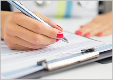 Close Up of Woman FIlling out Paper Work - The Super Dentists