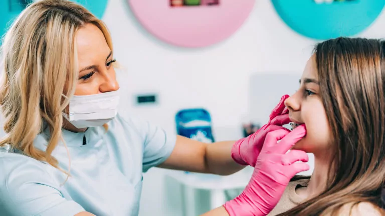 Orthodontist Checking Girls Dental Braces