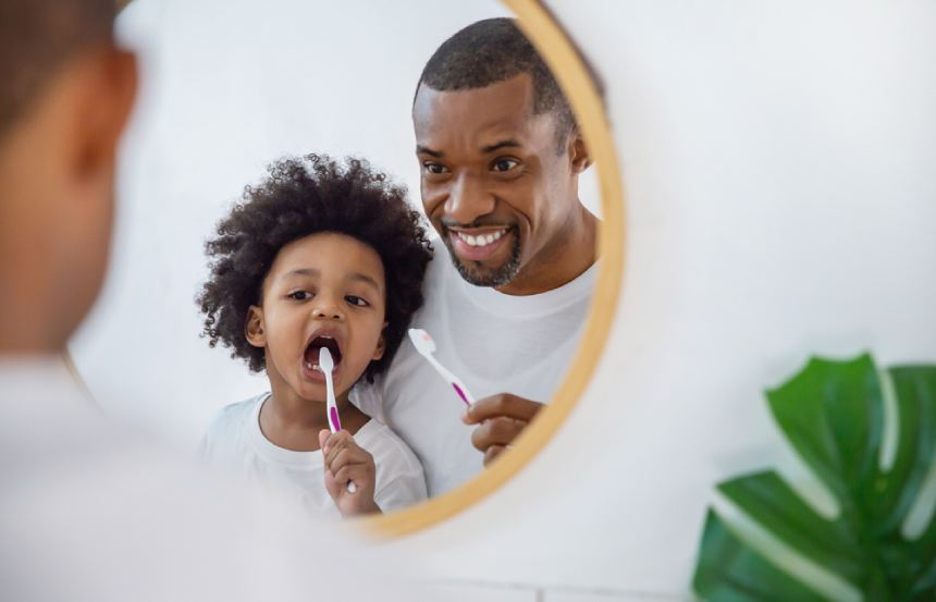 Happy father and son brushing teeth