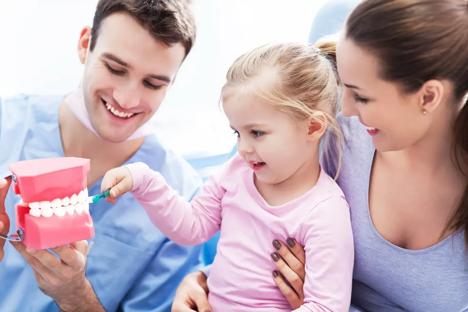 Mother & Pediatric Dentist in Dental Office with Diagram of Teeth Teaching Toddler how to Brush - The Super Dentists
