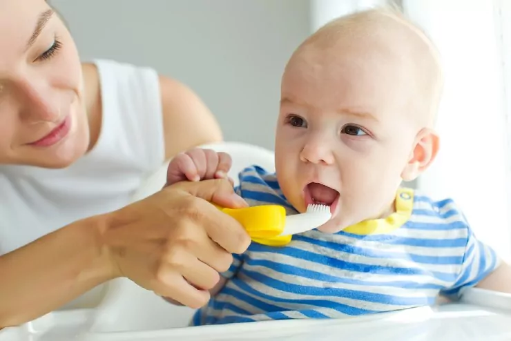 Mother brushing baby teeth