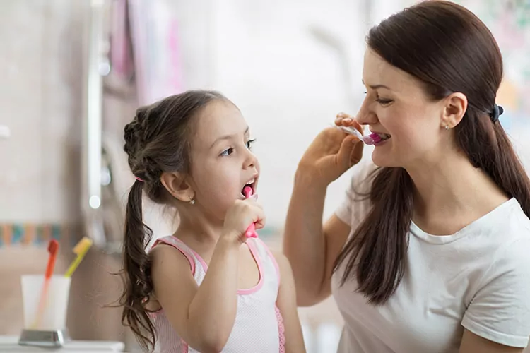 Mother and daughter brushing teeth together