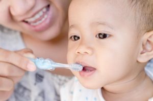 Mom helping baby brush their teeth