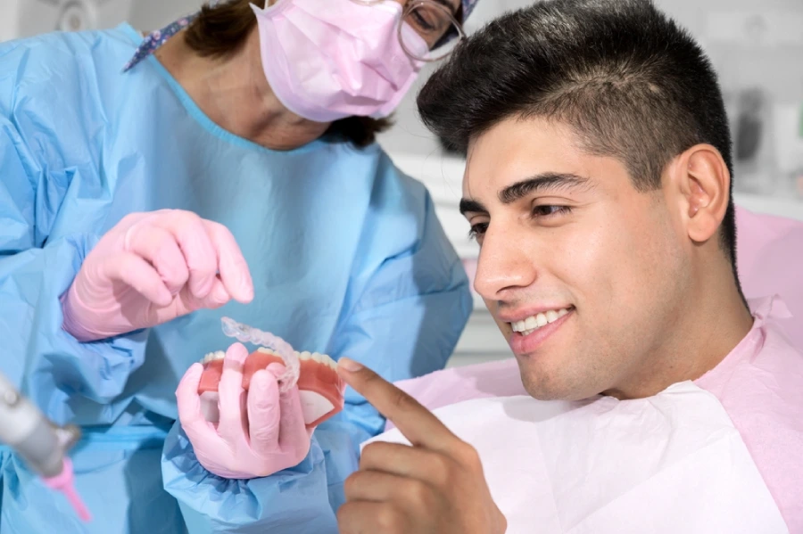 Dentist shows young man clear aligners during initial braces consultation