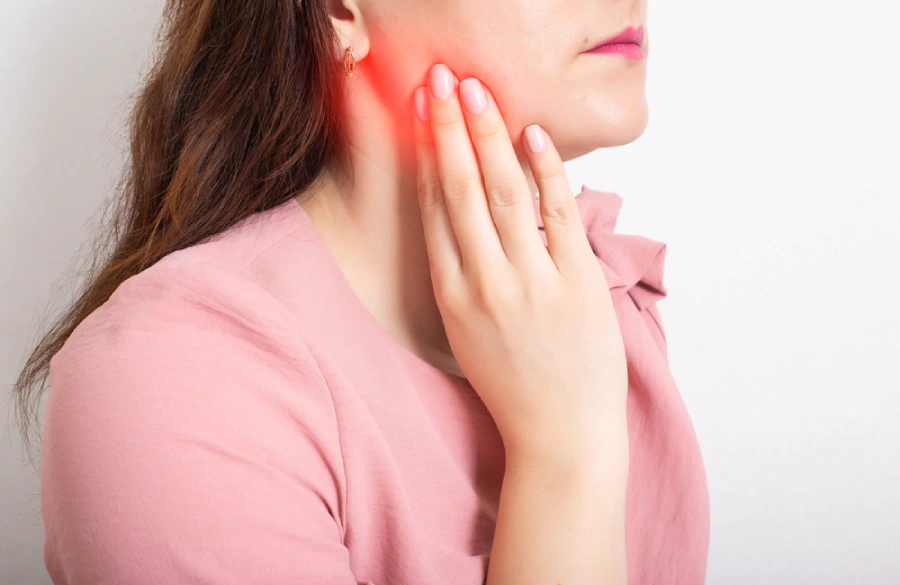 Woman touches the side of her face where she’s experiencing pain due to the growth of her wisdom teeth