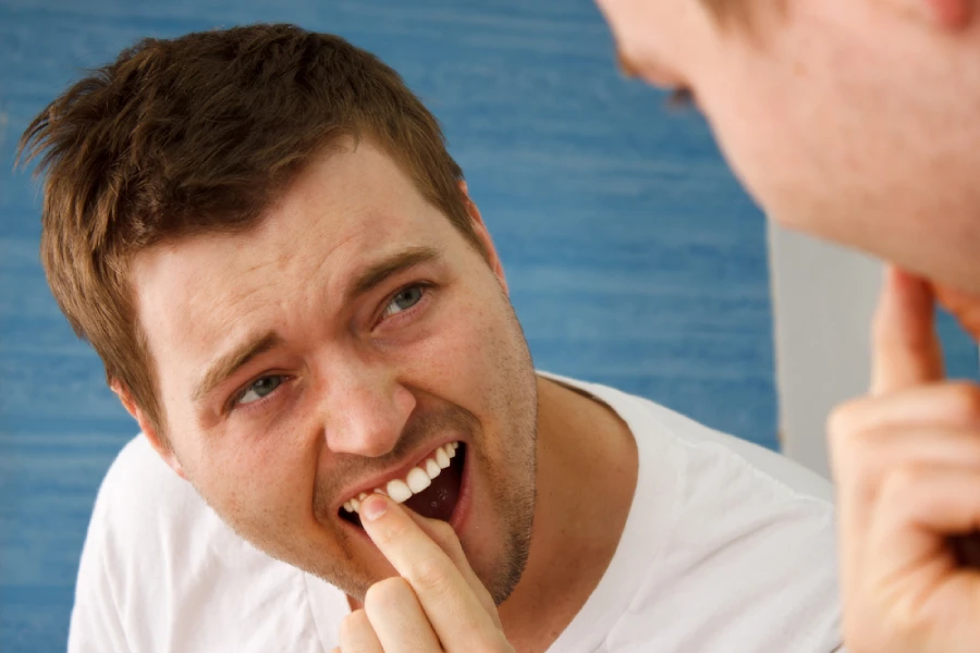 Caucasian man in white t-shirt wiggles loose front adult tooth