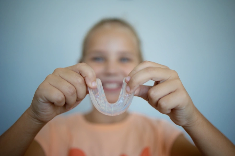 Young caucasian girl blurred out holds up a mouthguard