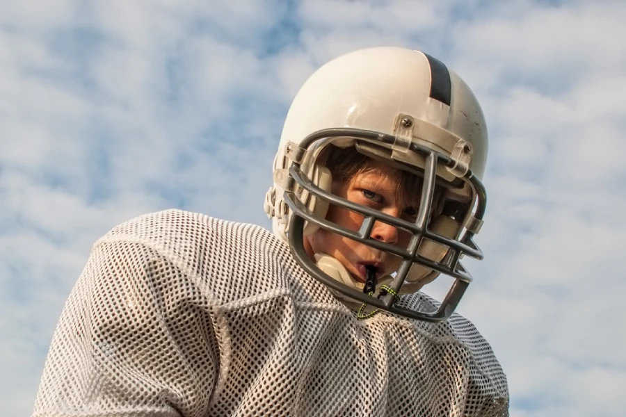Young blonde caucasian boy wears football helmet and mouthguard
