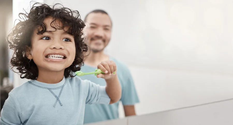 Dad brushing teeth with young son