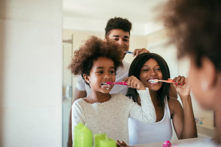 Happy African American family brushes their teeth together as part of a back to school dental health routine