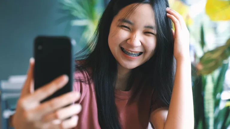 A young teenage girl smiles while wearing braces