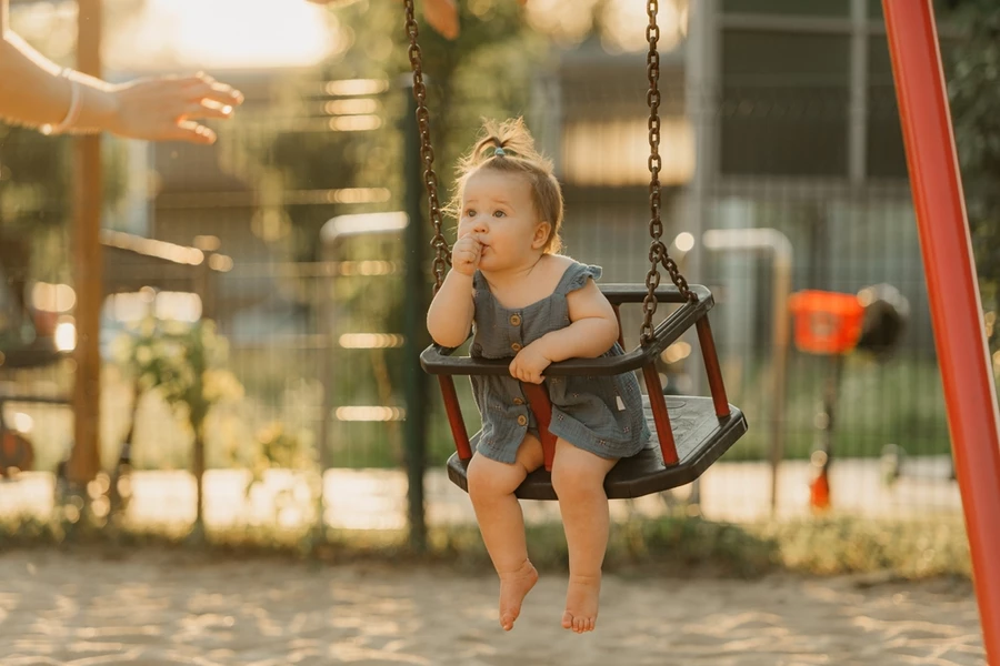 Young toddler in a swing sucks her thumb