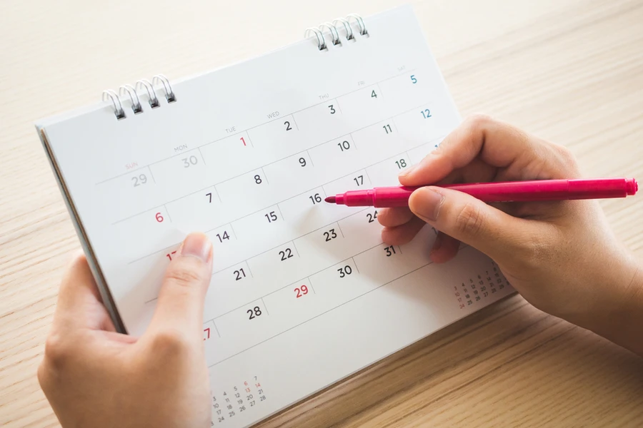 Hand with pen writing on calendar marking off a date for a routine dental checkup appointment