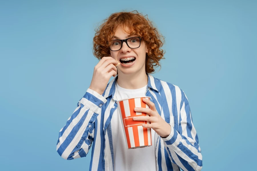 Young boy chews popcorn while wearing braces