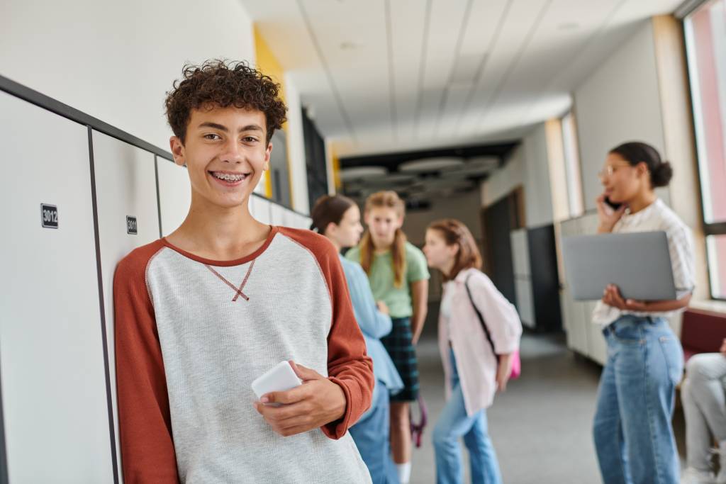 Teen with braces smiling by his locker at school