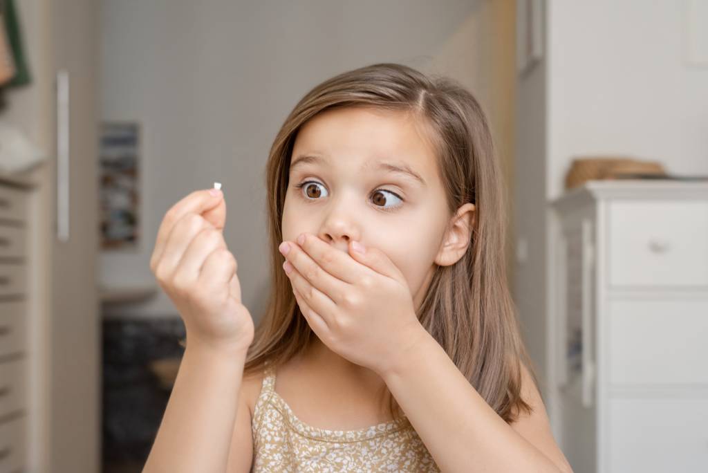 Young girl who has lost a tooth gasps and covers her mouth