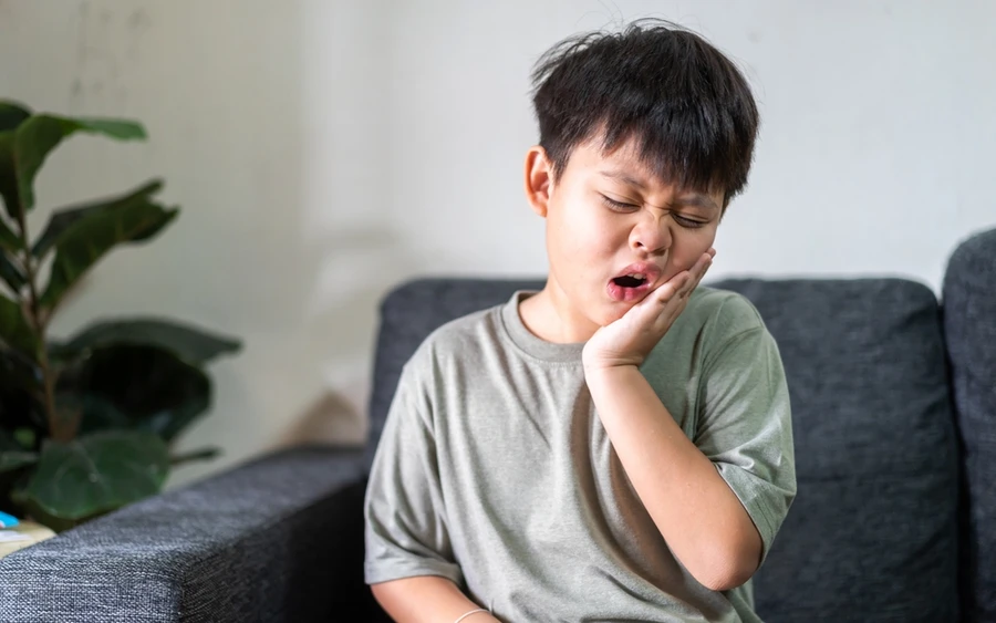 Young boy experiences a toothache due to cavities