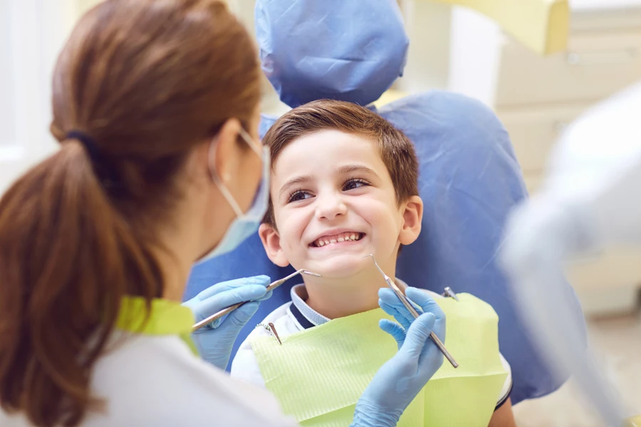 Young boy smiles as a dentist prepares to examine his teeth