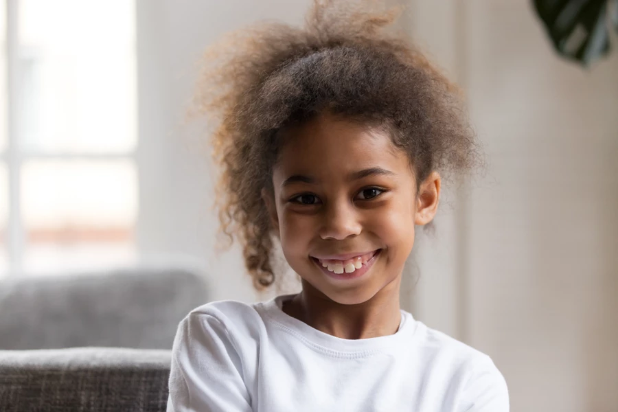 Young girl with permanent front teeth surrounded by baby teeth in smiles