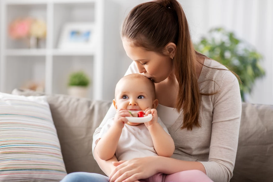 Mother kisses the head of her teething toddler