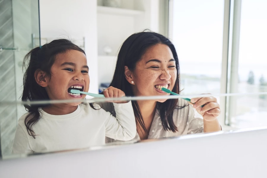 Mother and daughter brush teeth together