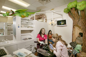 Pediatric Dentist Working on Patient Surrounded by Dental Assistants - The Super Dentists